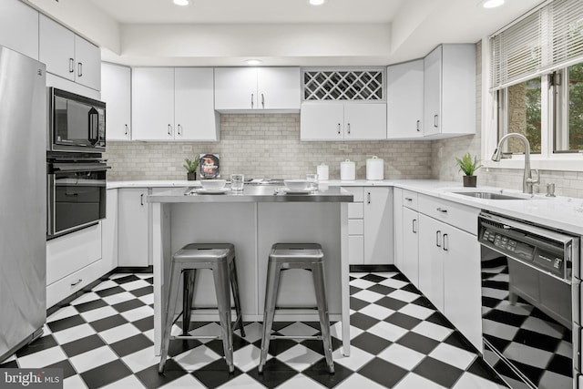 kitchen with white cabinets, a kitchen bar, sink, and black appliances