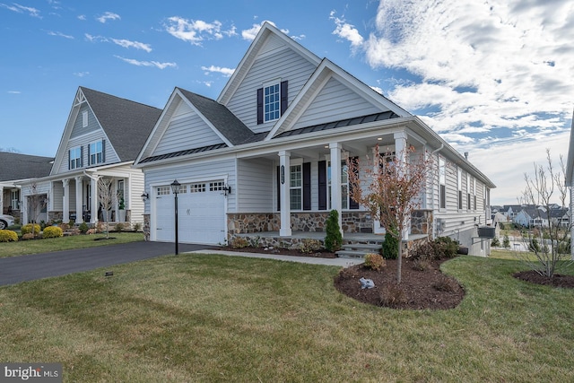 view of front of property featuring covered porch, a garage, and a front yard