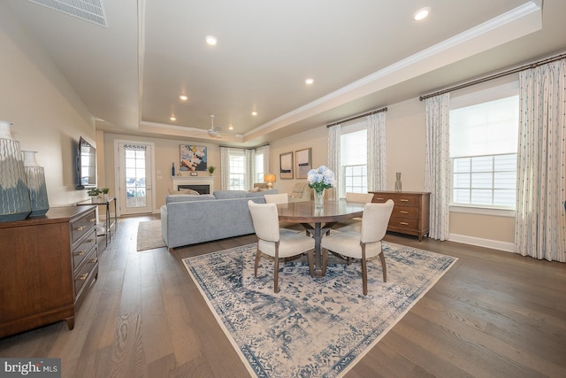 dining space featuring dark hardwood / wood-style floors, ceiling fan, crown molding, and a tray ceiling