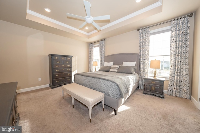 carpeted bedroom with a tray ceiling, multiple windows, crown molding, and ceiling fan