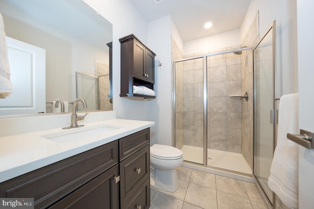 bathroom featuring tile patterned flooring, vanity, toilet, and a shower with shower door