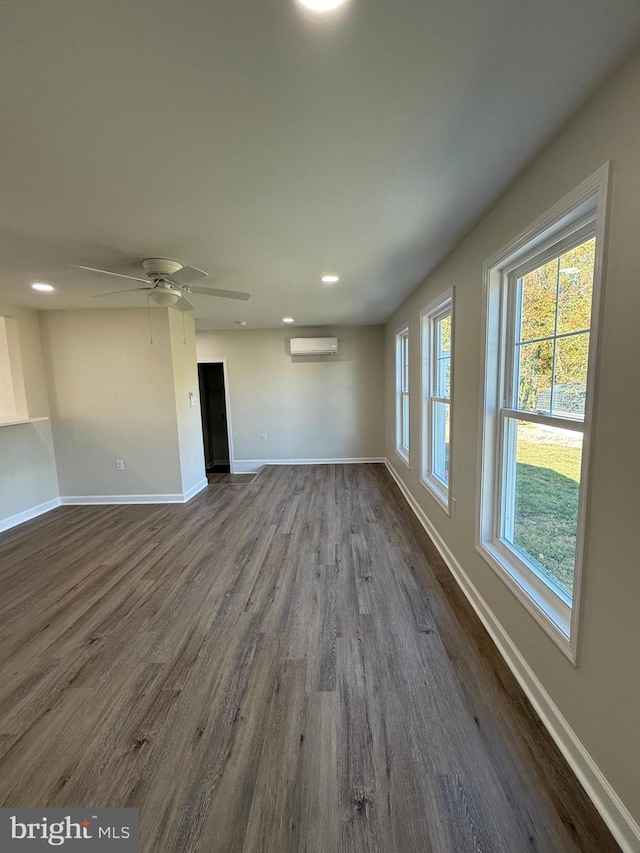 unfurnished living room with a wall unit AC, ceiling fan, and dark hardwood / wood-style flooring