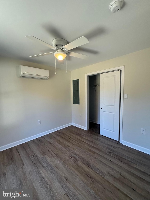 unfurnished bedroom with electric panel, dark wood-type flooring, a wall mounted air conditioner, and ceiling fan