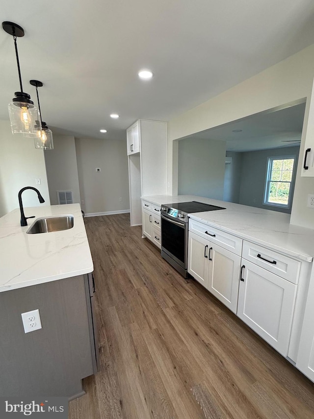 kitchen with stainless steel range with electric stovetop, sink, light stone countertops, white cabinets, and dark hardwood / wood-style flooring