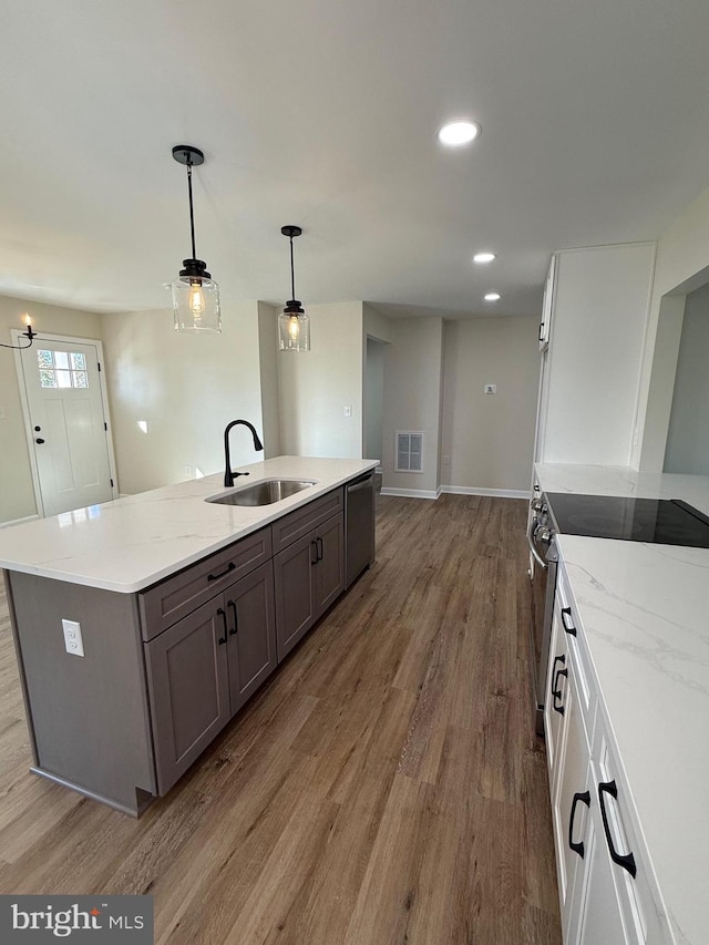 kitchen featuring sink, white cabinetry, stainless steel appliances, pendant lighting, and hardwood / wood-style flooring