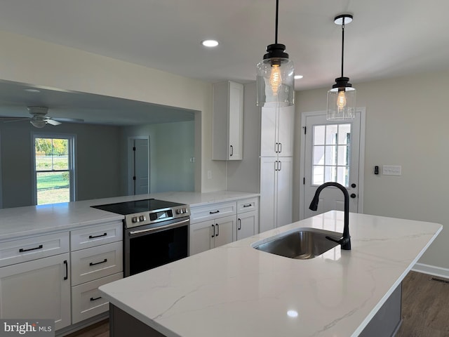 kitchen with sink, pendant lighting, an island with sink, and stainless steel electric range oven