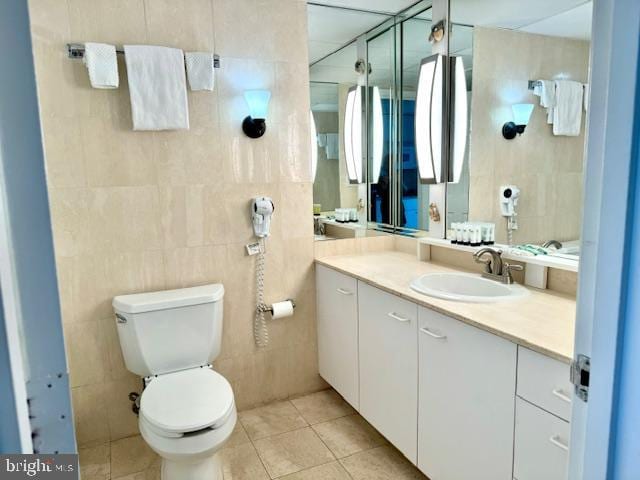 bathroom with toilet, vanity, and tile walls