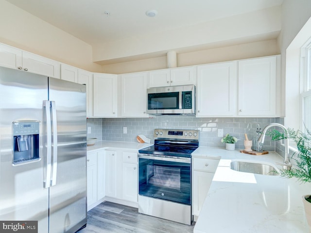 kitchen with sink, white cabinets, stainless steel appliances, and light wood-type flooring