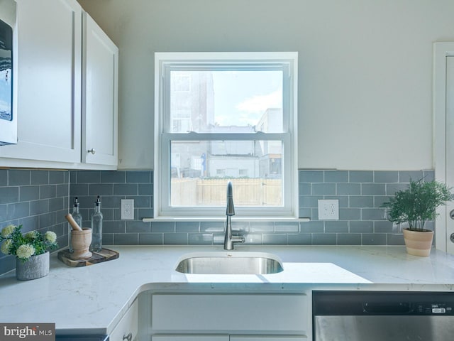 kitchen featuring stainless steel dishwasher, sink, white cabinets, and plenty of natural light