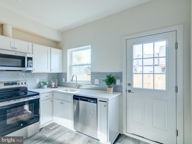 kitchen with stainless steel appliances, sink, light wood-type flooring, and white cabinets