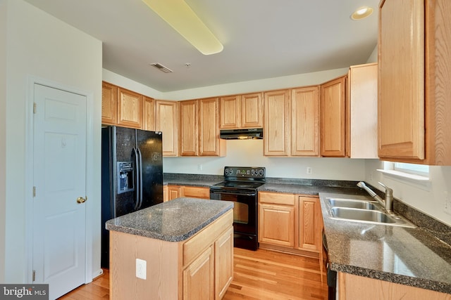 kitchen featuring sink, light hardwood / wood-style floors, black appliances, and a center island