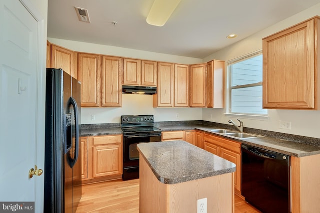 kitchen with light hardwood / wood-style floors, a center island, black appliances, and sink