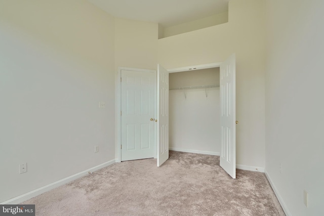 unfurnished bedroom featuring a closet and light colored carpet