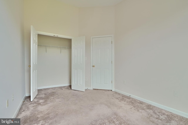 unfurnished bedroom with a closet, light carpet, and a high ceiling