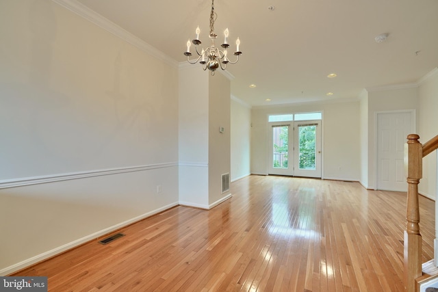 empty room with an inviting chandelier, light hardwood / wood-style flooring, and ornamental molding