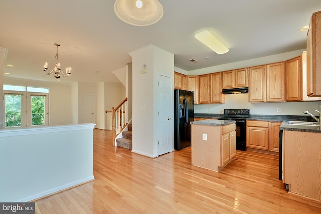 kitchen featuring black appliances, sink, light wood-type flooring, a center island, and hanging light fixtures