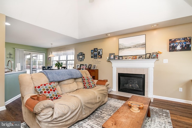 living room featuring hardwood / wood-style flooring, sink, and a tiled fireplace