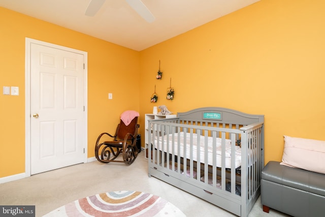 bedroom featuring a crib, carpet floors, and ceiling fan