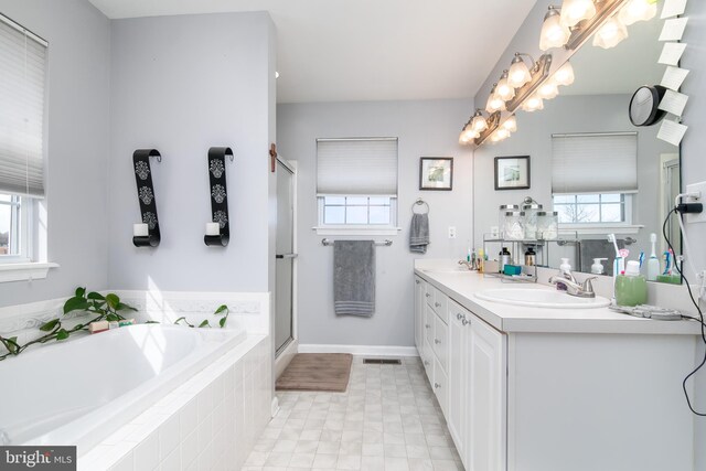 bathroom featuring vanity, independent shower and bath, and a wealth of natural light