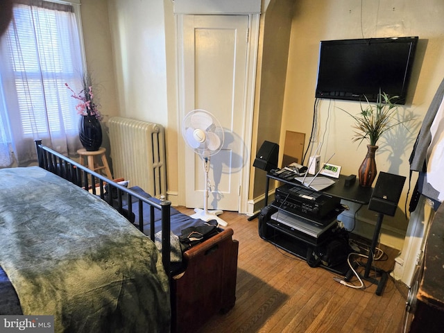 bedroom with wood-type flooring and radiator heating unit