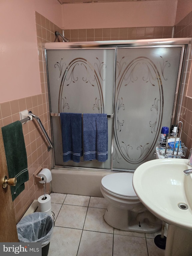 bathroom with tile patterned floors, sink, toilet, and tile walls