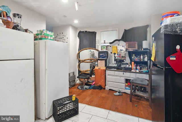 kitchen featuring black fridge, white fridge, and light wood-type flooring