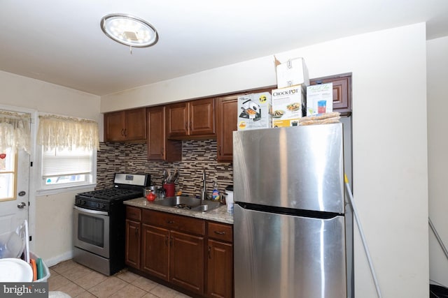 kitchen featuring sink, light stone counters, decorative backsplash, light tile patterned floors, and appliances with stainless steel finishes