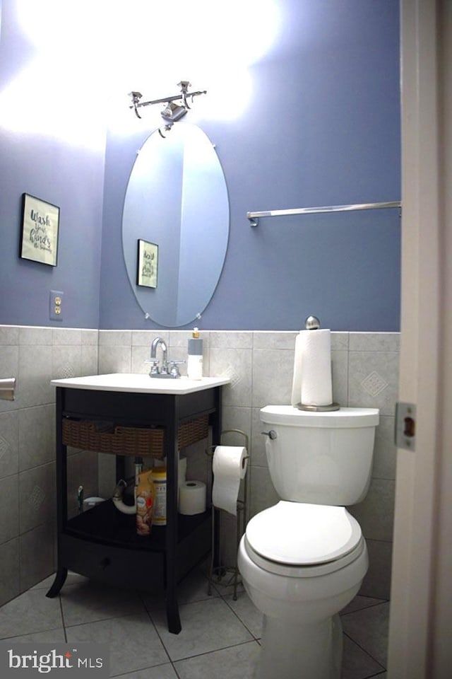 bathroom with toilet, tile walls, and tile patterned flooring