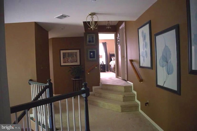 hall with carpet and an inviting chandelier