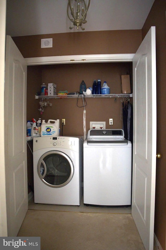 clothes washing area with a chandelier and washer and dryer