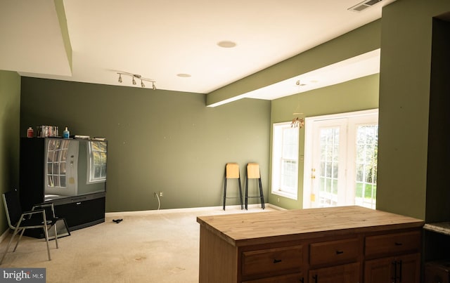 kitchen featuring wooden counters, dark brown cabinets, hanging light fixtures, and light carpet