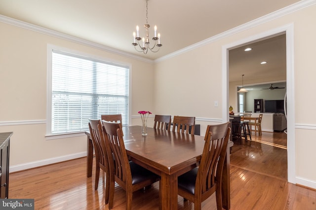 dining area with hardwood / wood-style floors, ceiling fan with notable chandelier, and crown molding