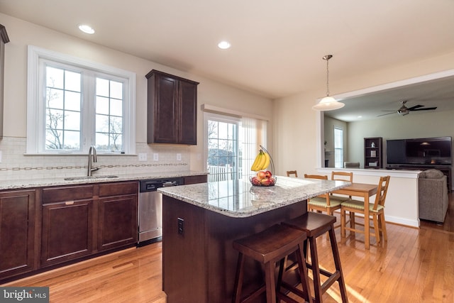 kitchen featuring light stone counters, sink, tasteful backsplash, stainless steel dishwasher, and light hardwood / wood-style flooring