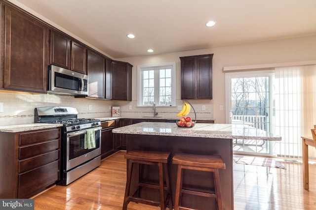 kitchen featuring dark brown cabinetry, appliances with stainless steel finishes, and light hardwood / wood-style flooring