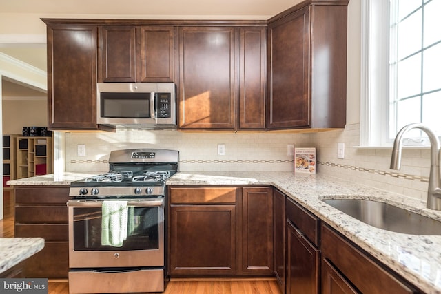 kitchen featuring light stone countertops, appliances with stainless steel finishes, sink, and light hardwood / wood-style floors