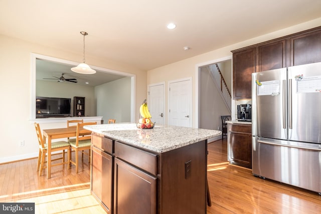 kitchen featuring light hardwood / wood-style floors, hanging light fixtures, a kitchen island, and stainless steel fridge