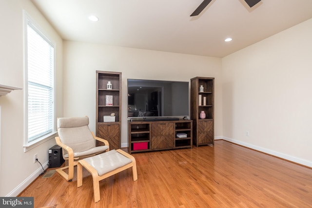 living area featuring light wood-type flooring, a wealth of natural light, and ceiling fan