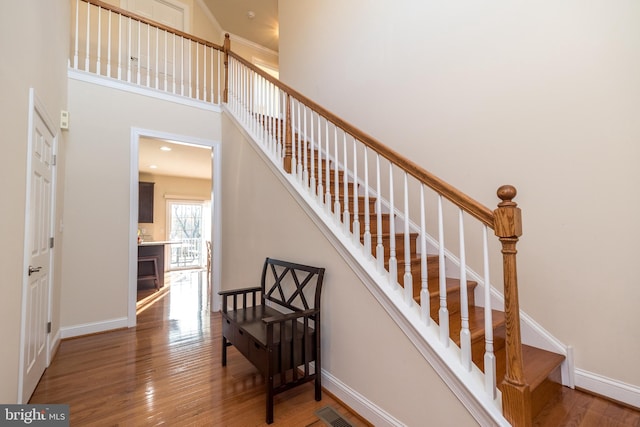 stairway with a high ceiling and wood-type flooring