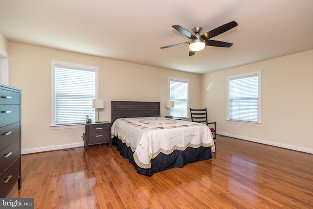 bedroom featuring multiple windows, hardwood / wood-style flooring, and ceiling fan