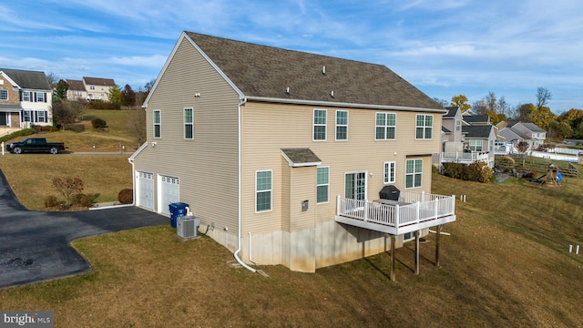 back of house featuring central air condition unit, a garage, a lawn, and a balcony