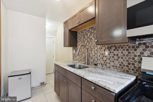 kitchen featuring stove, decorative backsplash, light tile patterned floors, and sink