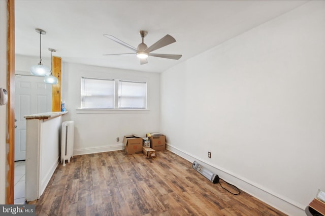 empty room featuring hardwood / wood-style floors, radiator, and ceiling fan