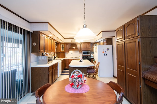 kitchen with a center island, decorative light fixtures, white appliances, custom range hood, and ornamental molding