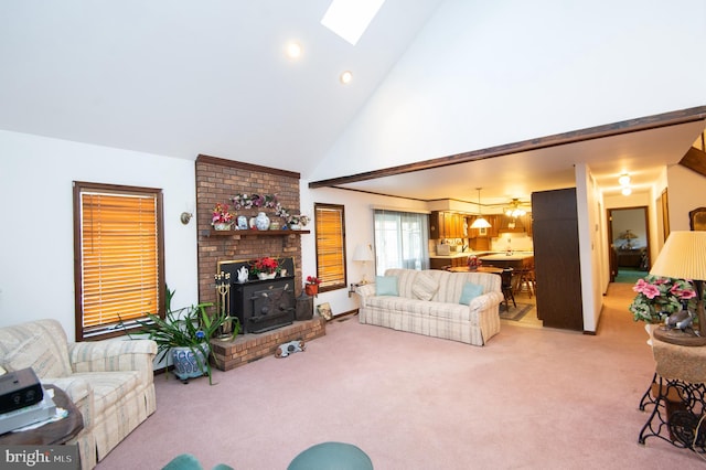 living room with carpet flooring, a skylight, high vaulted ceiling, and a wood stove