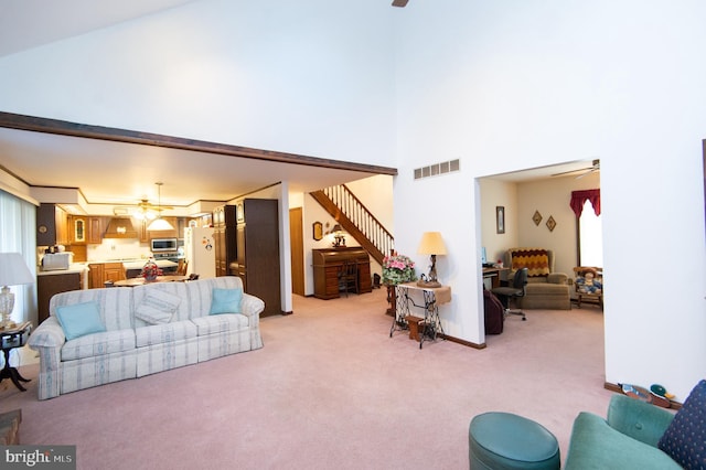 carpeted living room with a high ceiling and ceiling fan