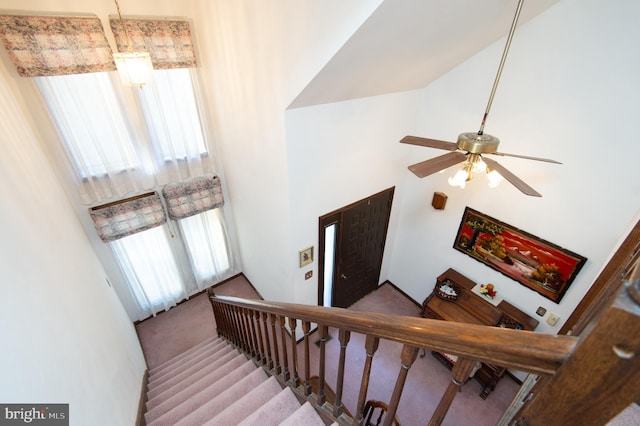 staircase with carpet floors, high vaulted ceiling, and ceiling fan