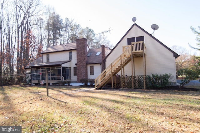 rear view of house with a lawn, a wooden deck, and a sunroom