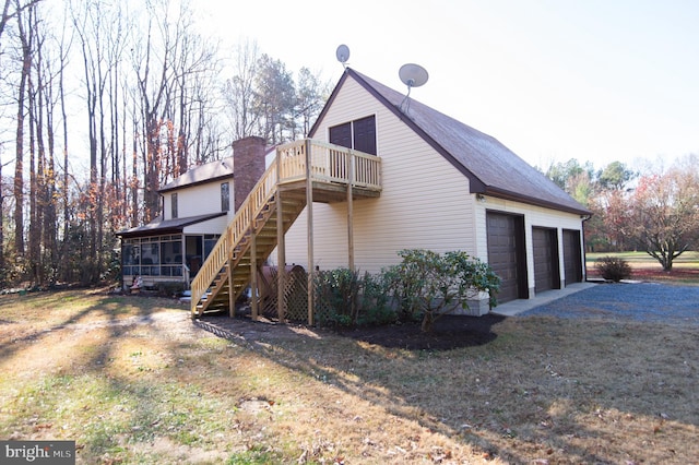 view of side of property with a balcony, a garage, a lawn, and a sunroom