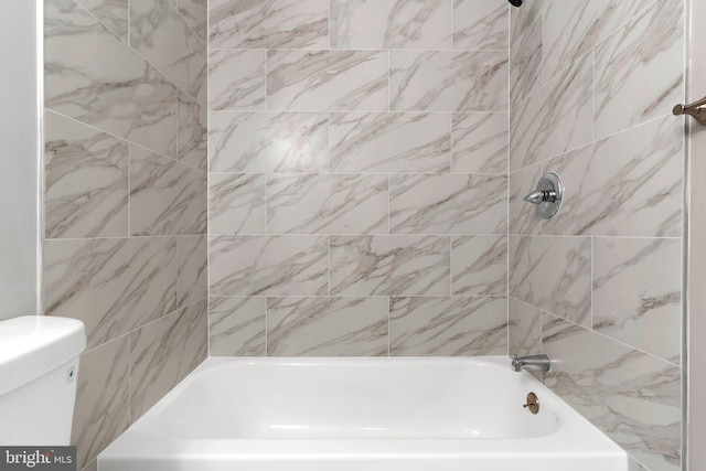 bathroom featuring tiled shower / bath and toilet