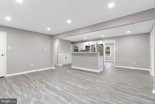 kitchen featuring stainless steel appliances, a center island, white cabinets, and light wood-type flooring